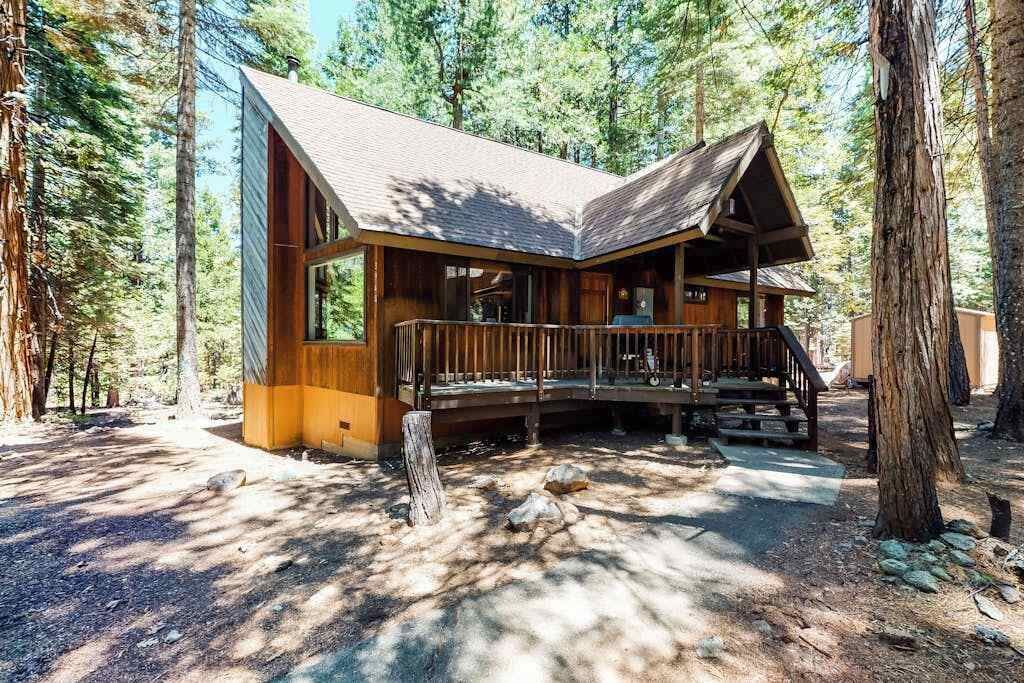 A cabin with a porch, surrounded by trees.