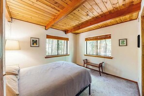 Una camera da letto con un letto, due finestre, una panca e una lampada.