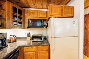 Una cucina compatta con mobili in legno, un forno a microonde, un tostapane e un frigorifero.