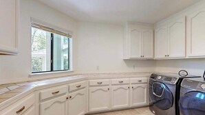 Una cocina con muebles blancos, una ventana y lavadora y secadora integradas.