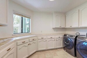 Una cocina con muebles blancos, una ventana y lavadora y secadora integradas.