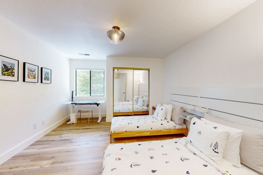 Ein Schlafzimmer mit zwei Betten, einem Schreibtisch und einem großen Spiegel.