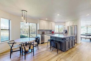 A modern kitchen with a central island, bar stools, and a dining area with a round table and chairs.