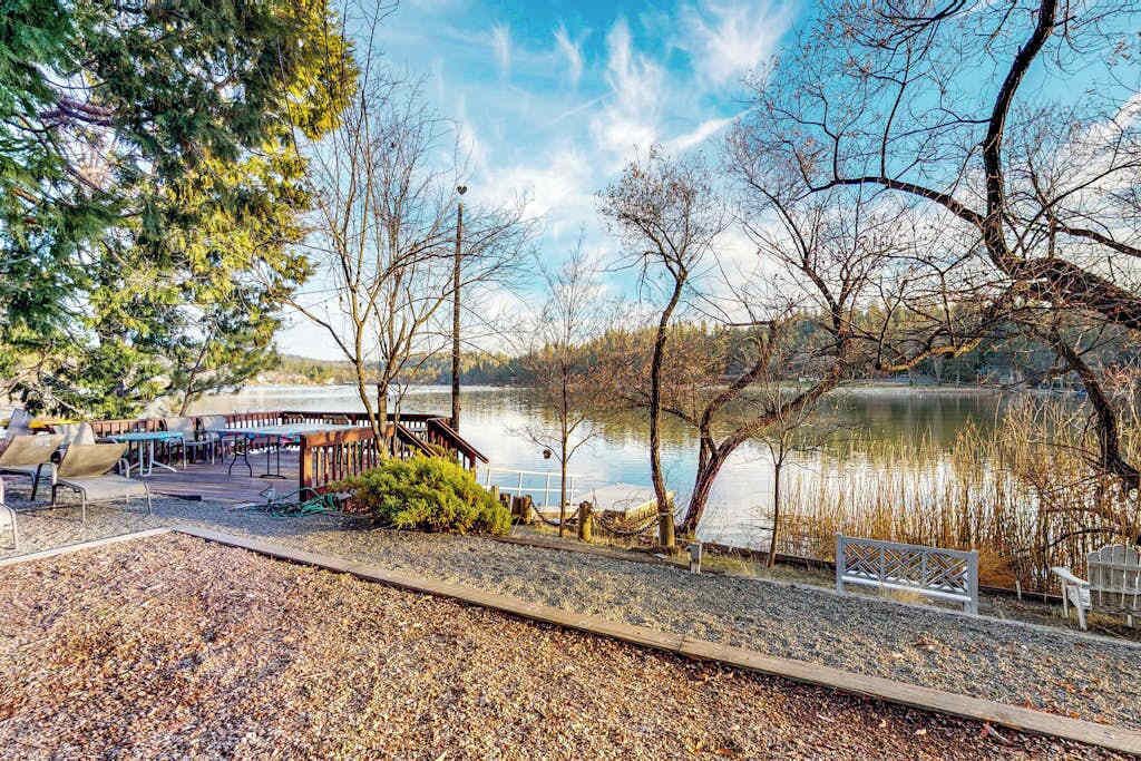 A lakeside area with a wooden deck, benches, and a gazebo overlooking the water.