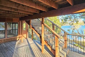 Eine Holzterrasse mit einer Treppe, die zu einem überdachten Bereich mit großen Fenstern führt.