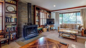 Una sala de estar acogedora con chimenea, televisor, sofá y estantería.