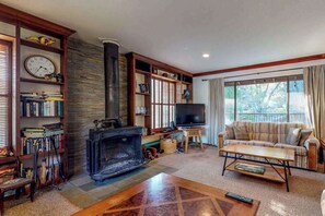 Ein gemütliches Wohnzimmer mit Kamin, Fernseher, einer Couch und einem Bücherregal.