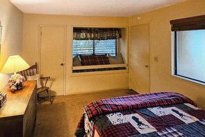 A bedroom with a bed, a desk with a lamp, a chair, and a window with blinds. - Heart's Desire on the Lake - Pine Mountain Lake (Groveland)