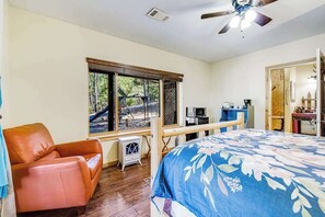 A bedroom with a bed, a chair, a desk, and a window with a view of trees. - The Cub Inn - Groveland (Groveland)