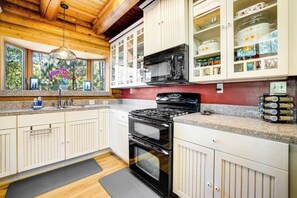 A kitchen with white cabinets, a black stove, and a microwave. - The Cub Inn - Groveland (Groveland)