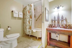 A bathroom with a toilet, shower, and wooden vanity with a sink. - The Cub Inn - Groveland (Groveland)