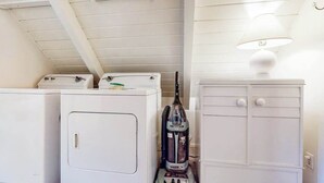 A laundry area with two white washing machines and a vacuum cleaner. - Mountain Memories - Musick Meadows (Shaver Lake)