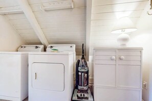 A laundry area with two white washing machines and a vacuum cleaner. - Mountain Memories - Musick Meadows (Shaver Lake)