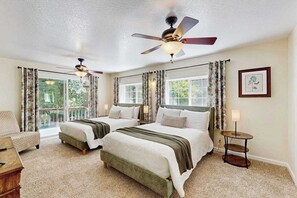 Ein Hotelzimmer mit zwei Betten, einem Deckenventilator, einem kleinen Tisch und Blick ins Freie.