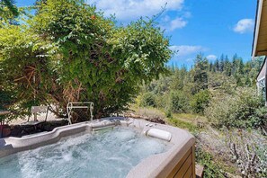 Un bain à remous entouré d’une végétation luxuriante, sous un ciel dégagé.