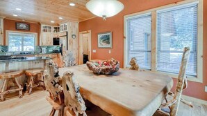 A spacious kitchen with wooden cabinets, a dining table, and a large window. - Pinnacle Point - Granite Ridge (Shaver Lake)