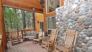 A wooden deck with several rocking chairs and a stone wall. - Pinnacle Point - Granite Ridge (Shaver Lake)