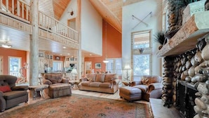 A spacious living area with a high ceiling, a fireplace, and a large rug. - Pinnacle Point - Granite Ridge (Shaver Lake)
