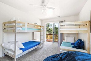 A room with bunk beds, a ceiling fan, and a view through a glass door to an outdoor area. - Big Creek Hideaway - Pine Mountain Lake (Groveland)