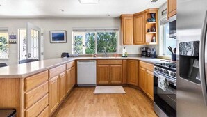 A kitchen with wooden cabinets, a stainless steel refrigerator, and a dishwasher. - Big Creek Hideaway - Pine Mountain Lake (Groveland)