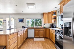 Eine Küche mit Holzausstattung, einem Edelstahlkühlschrank und einem Geschirrspüler.