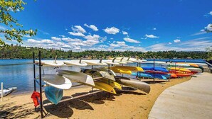 A row of canoes and kayaks on a sandy beach by a calm lake with a clear sky. - Big Creek Hideaway - Pine Mountain Lake (Groveland)