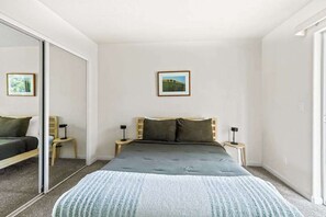 A bedroom with a bed, a bedside table, a nightstand, a mirror, and a framed picture on the wall. - Big Creek Hideaway - Pine Mountain Lake (Groveland)