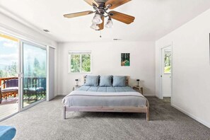 Un dormitorio con una cama grande, ventilador de techo y vistas a una terraza.