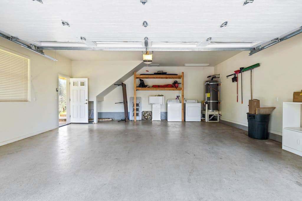A spacious garage with a loft bed, a workbench, and various tools.
