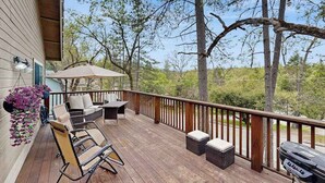 Eine Holzterrasse mit Gartenmöbeln, einem Grill und hängenden Blumenkörben.