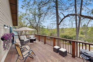 Eine Holzterrasse mit Gartenmöbeln, einem Grill und hängenden Blumenkörben.