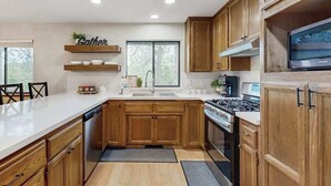 Eine moderne Küche mit Holzausstattung, einem Edelstahlherd und einem eingebauten Backofen.
