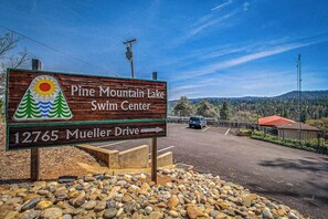 En träskylt för Pine Mountain Lakes badcenter, med en pil som pekar mot Mueller Drive.