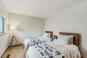 A hotel room with two beds, a bedside table with a lamp, and a window. - Harmony Haven - Pine Mountain Lake (Groveland)