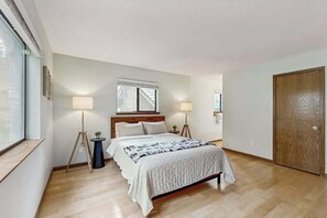 Ein Schlafzimmer mit Bett, Nachttischlampen, einem Fenster und einer Tür.