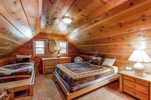 Ein gemütliches Schlafzimmer im Dachgeschoss mit zwei Betten, einem Schminktisch und einem Nachttisch.