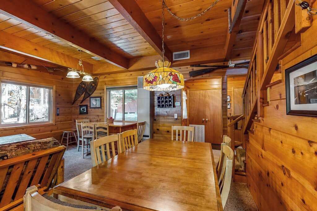 A wooden interior with a dining table, chairs, and a chandelier.