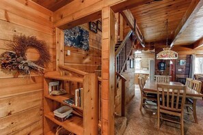 Un intérieur en bois avec un escalier, un coin repas et une cheminée.
