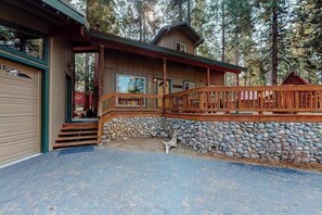 A two-story cabin with a stone foundation, a wooden deck, and a garage.