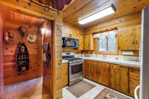 A compact kitchen with wooden cabinets, a microwave, stove, and a refrigerator.