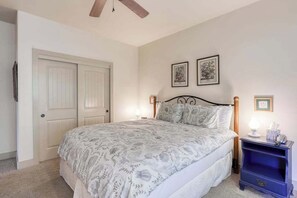 A bedroom with a bed, two framed pictures on the wall, a nightstand with a lamp, and a door. - Alder Hill Hideaway - Wildflower Village (Shaver Lake)