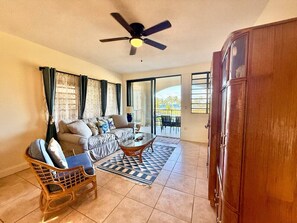 A living room with a sofa, a coffee table, a ceiling fan, and a view through a glass door. - Sunset Oasis - 2Br Beach Front Condo (Christiansted)