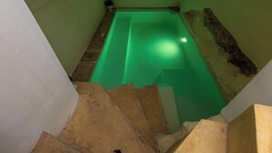 A narrow staircase leading to a green-lit swimming pool area with a small statue on the wall. - AquaTerrae by BarbarHouse (Alezio)