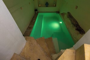A narrow staircase leading to a green-lit swimming pool area with a small statue on the wall. - AquaTerrae by BarbarHouse (Alezio)