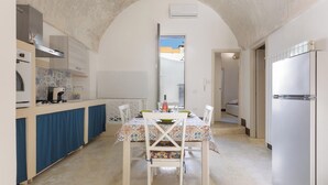 A compact kitchen with a dining area, featuring a central island, a built-in oven, and a refrigerator. - AquaTerrae by BarbarHouse (Alezio)
