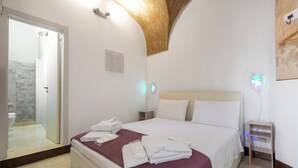 A hotel room with a bed, a bedside table, a wall-mounted light, and a door leading to a bathroom. - AquaTerrae by BarbarHouse (Alezio)