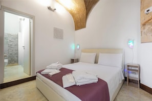 A hotel room with a bed, a bedside table, a wall-mounted light, and a door leading to a bathroom. - AquaTerrae by BarbarHouse (Alezio)