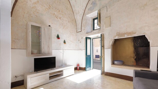 A living room with a television on a wooden stand, a fireplace, and a door leading outside. - AquaTerrae by BarbarHouse (Alezio)
