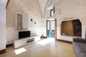 Un salon avec un téléviseur posé sur un meuble en bois, une chemin ée et une porte donnant sur l’extérieur.