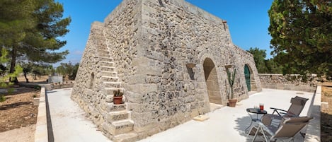 A stone building with a staircase, a door, and a small table with chairs.
